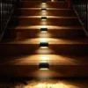 Solar Step Lights on Wooden Stairs Night View Outdoor solar step lights installed on wooden stairs, warm white LED illumination for patio and garden safety lighting