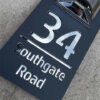 Close-up of personalised house number plaque 34 Southgate Road, 3D silver letters on black matte base