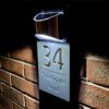Side view of lit personalised house number plaque 34 Southgate Road, LED sign on brick wall at night