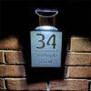 Illuminated personalised house number plaque 34 Southgate Road, lit LED sign on brick wall at night
