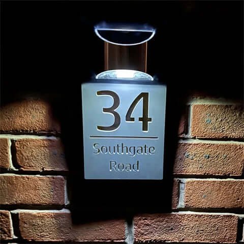 Illuminated personalised house number plaque 34 Southgate Road, lit LED sign on brick wall at night