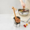 Utensil Rack In Cooking Scene Stainless steel multi-purpose kitchen utensil rack lid holder holding wooden cooking spoon beside cooking pot